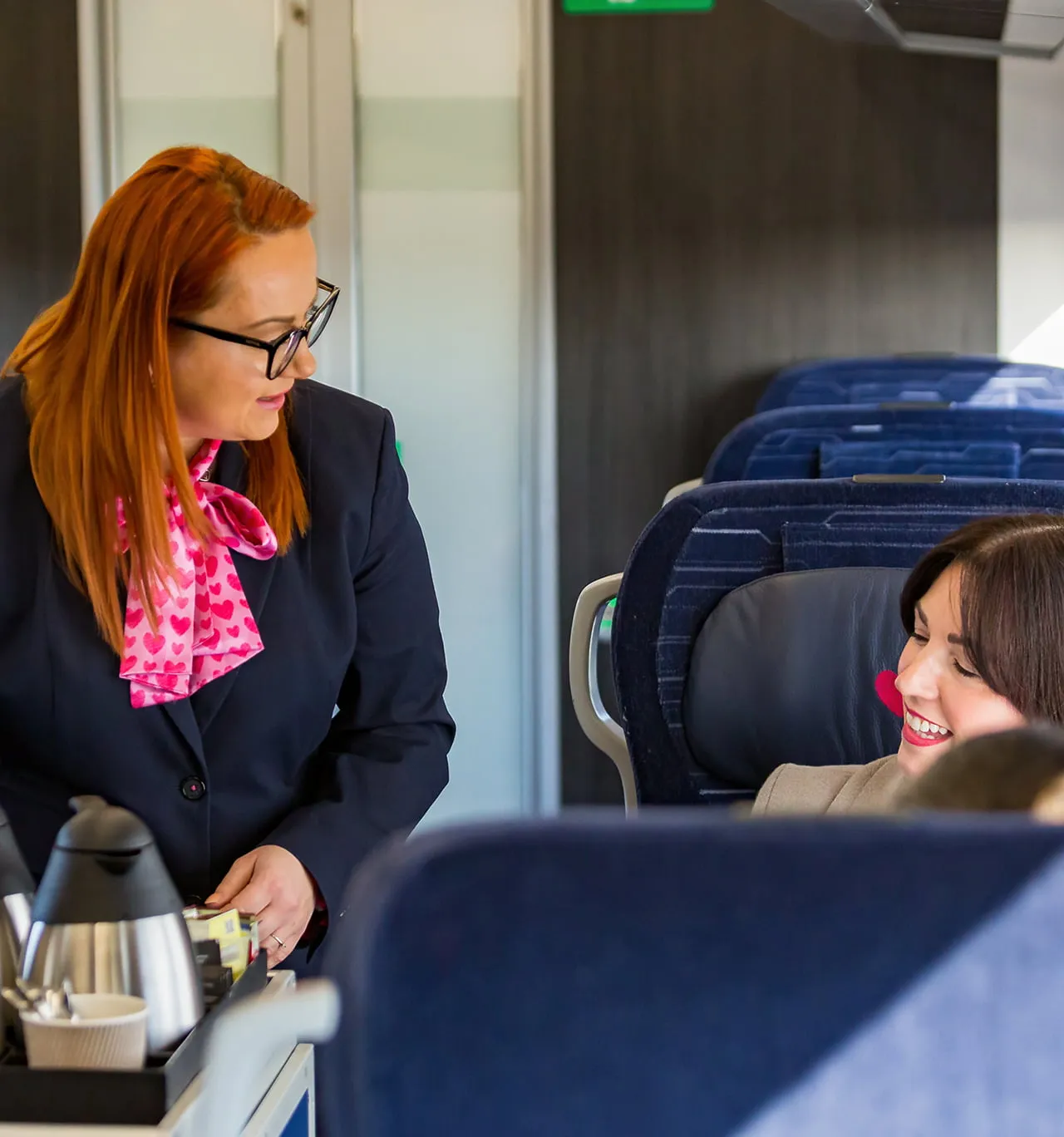 A customer travelling in First Class being offered a hot drink from the trolley