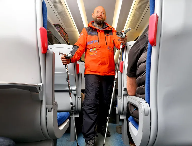 A man in an orange jacket standing in the aisle of a Hull Trains service
